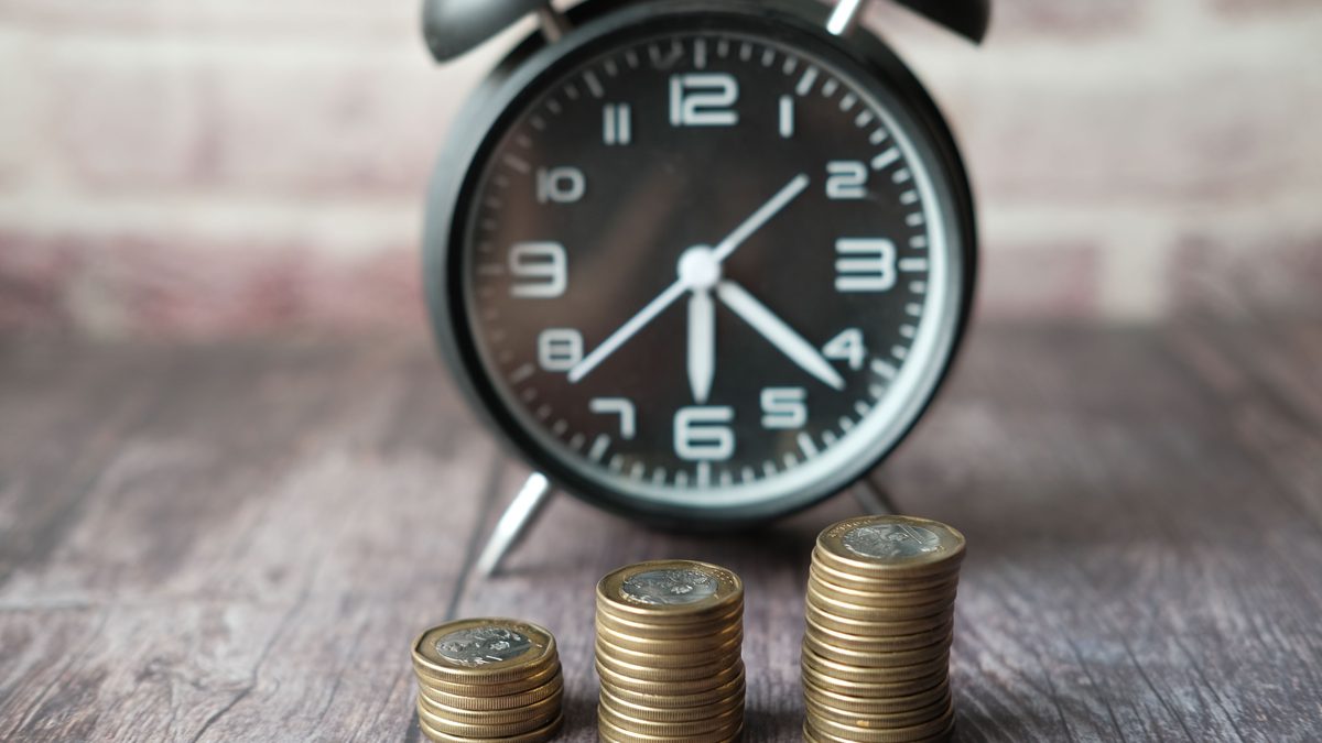 Stacked coins and a classic alarm clock symbolize the value of time and money.