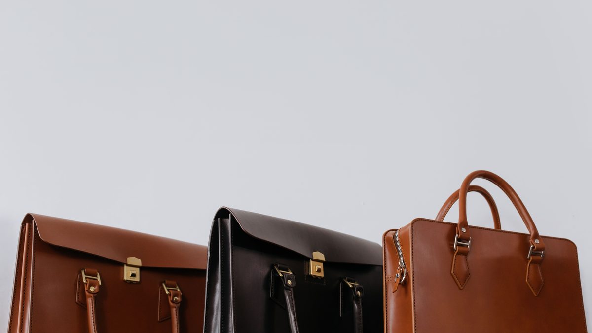 Three leather briefcases photographed close up and side by side in warm light.