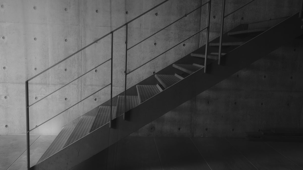 Black and white photo of an industrial metal staircase against a concrete wall.