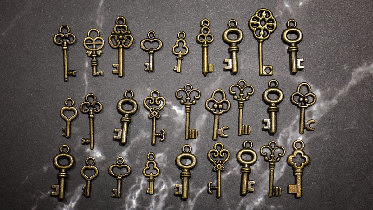 A collection of antique skeleton keys on a textured marble surface, offering a vintage aesthetic.