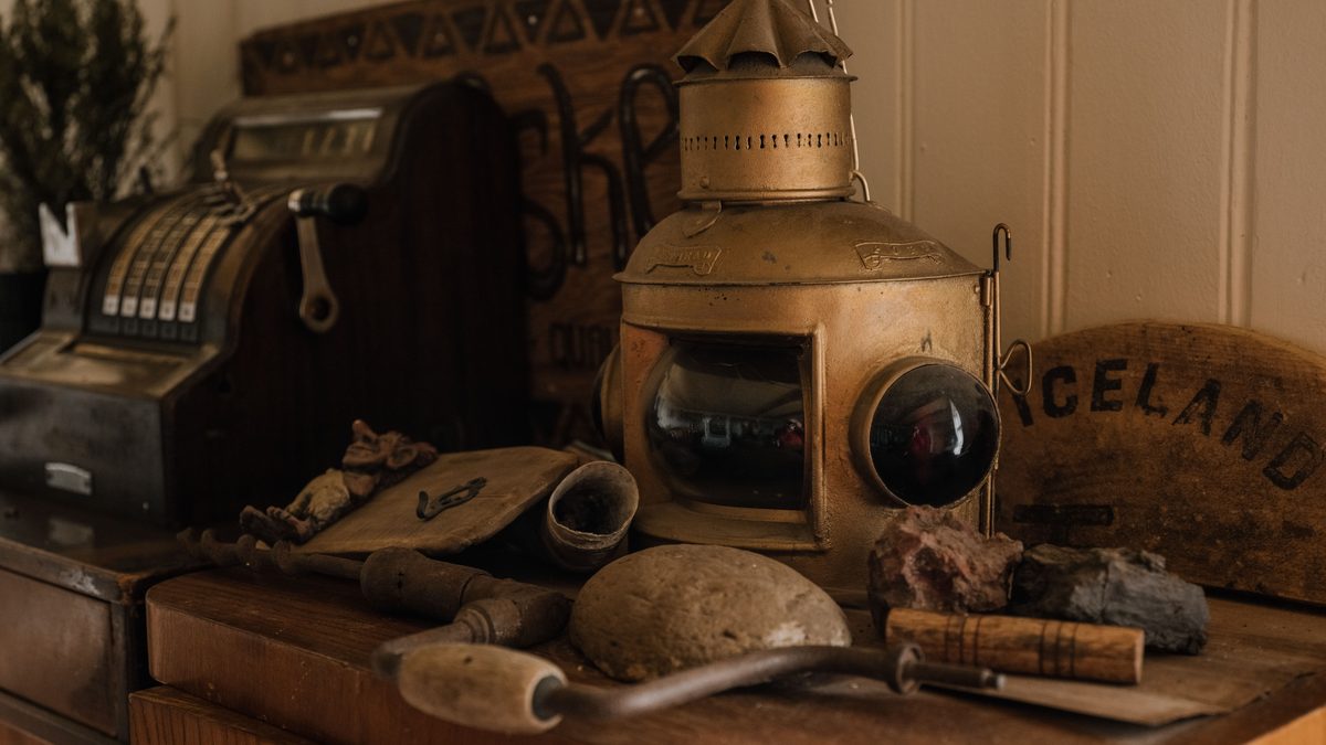 A collection of vintage items including a cash register and a lantern on a wooden cabinet.
