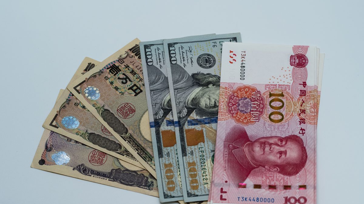Various international currency notes including US dollars, yen, and yuan arranged on a surface.