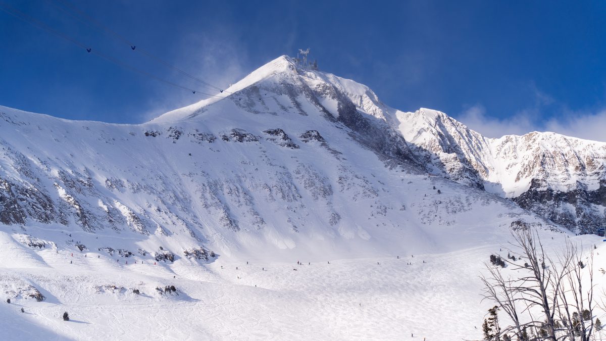 Capture of skiers on a snowy mountain under the clear blue sky in Montana, USA.