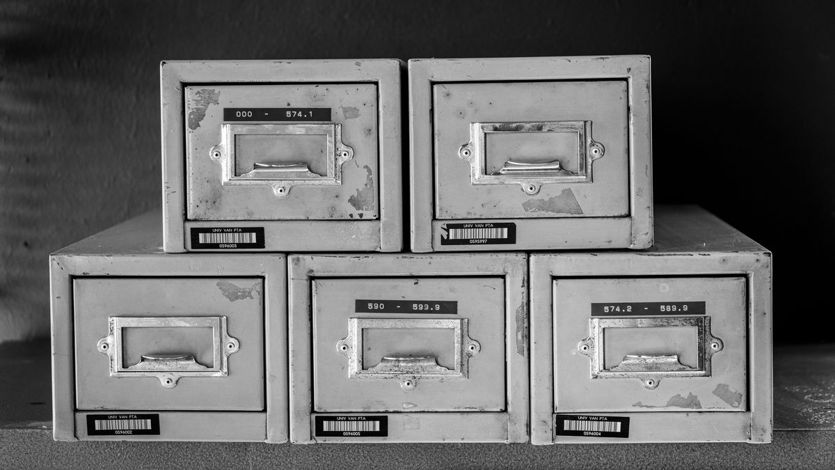 A set of five vintage metal file cabinets, aged and worn, displayed in black and white.