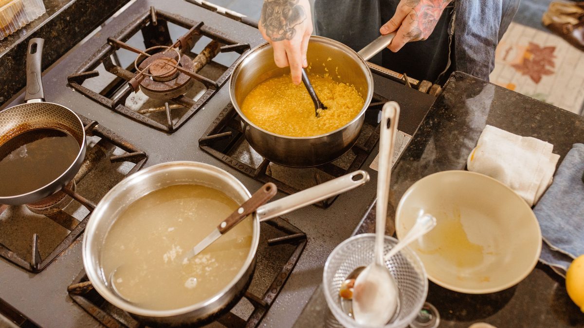 Professional chef stirring ingredients on a gas stove in a modern kitchen setting, showcasing skillful culinary preparation.