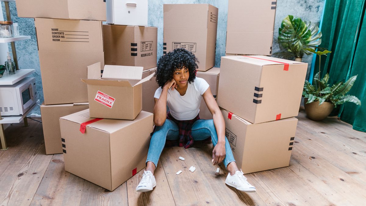 A young woman sitting among cardboard boxes, indicating moving day.