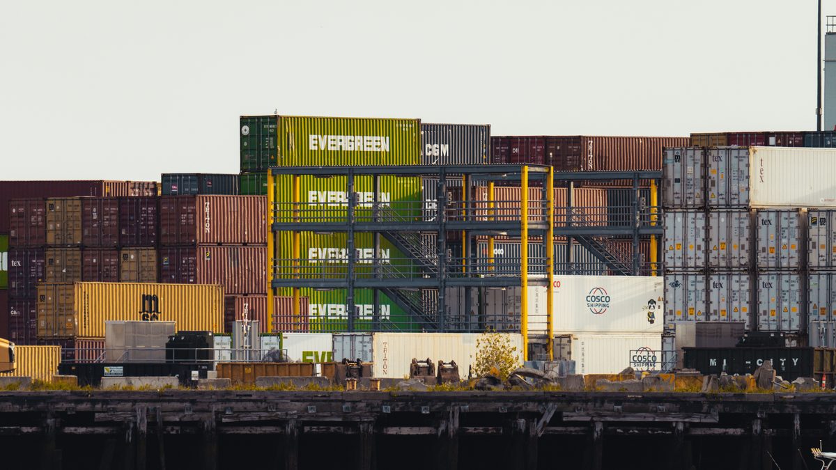 Colorful shipping containers stacked at a busy seaside dock.