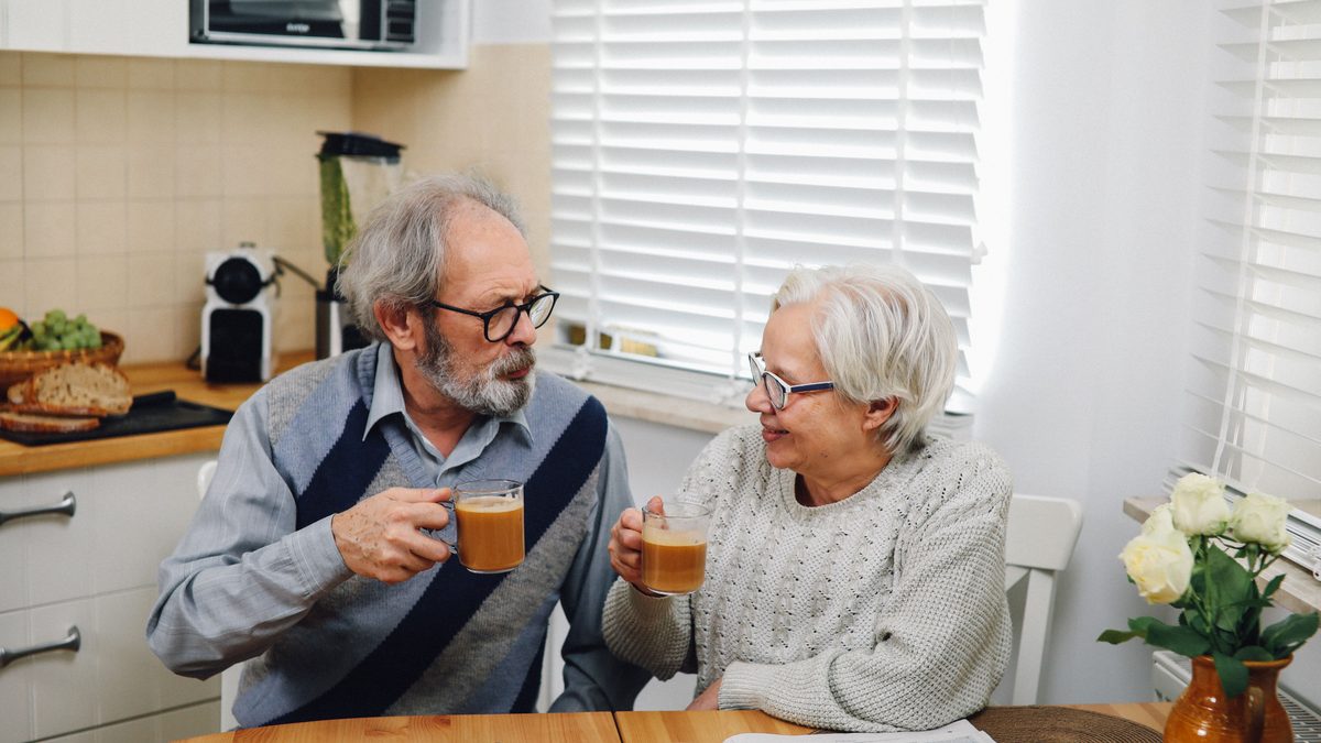 Senior couple enjoying coffee together at home in cozy kitchen setting.