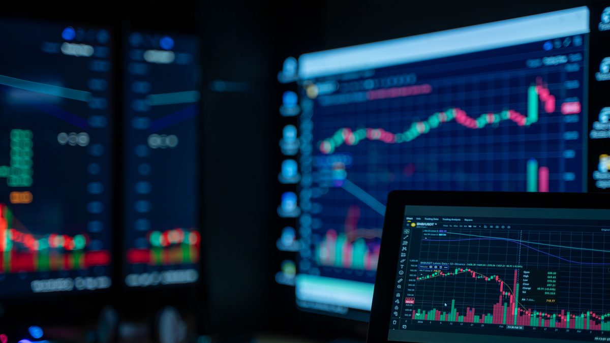 Monitors displaying stock market charts in a dimly lit room, perfect for finance and trading themes.