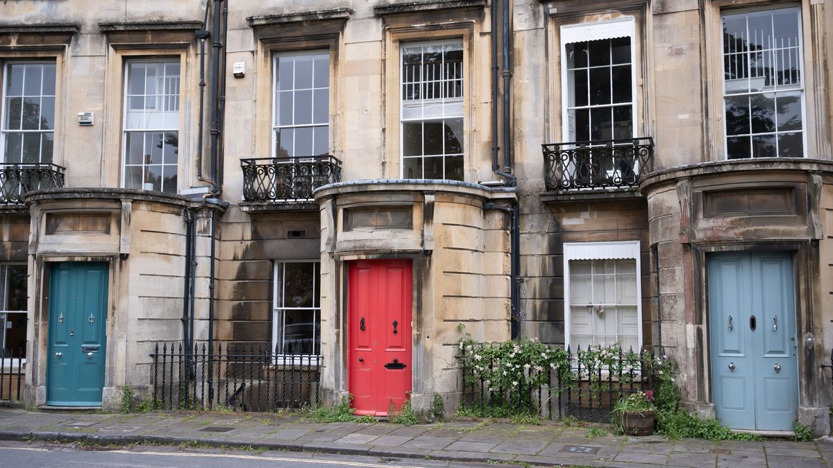 A terrace of Georgian brick row houses with brightly painted front doors, photographed along the pavement of a historic street.