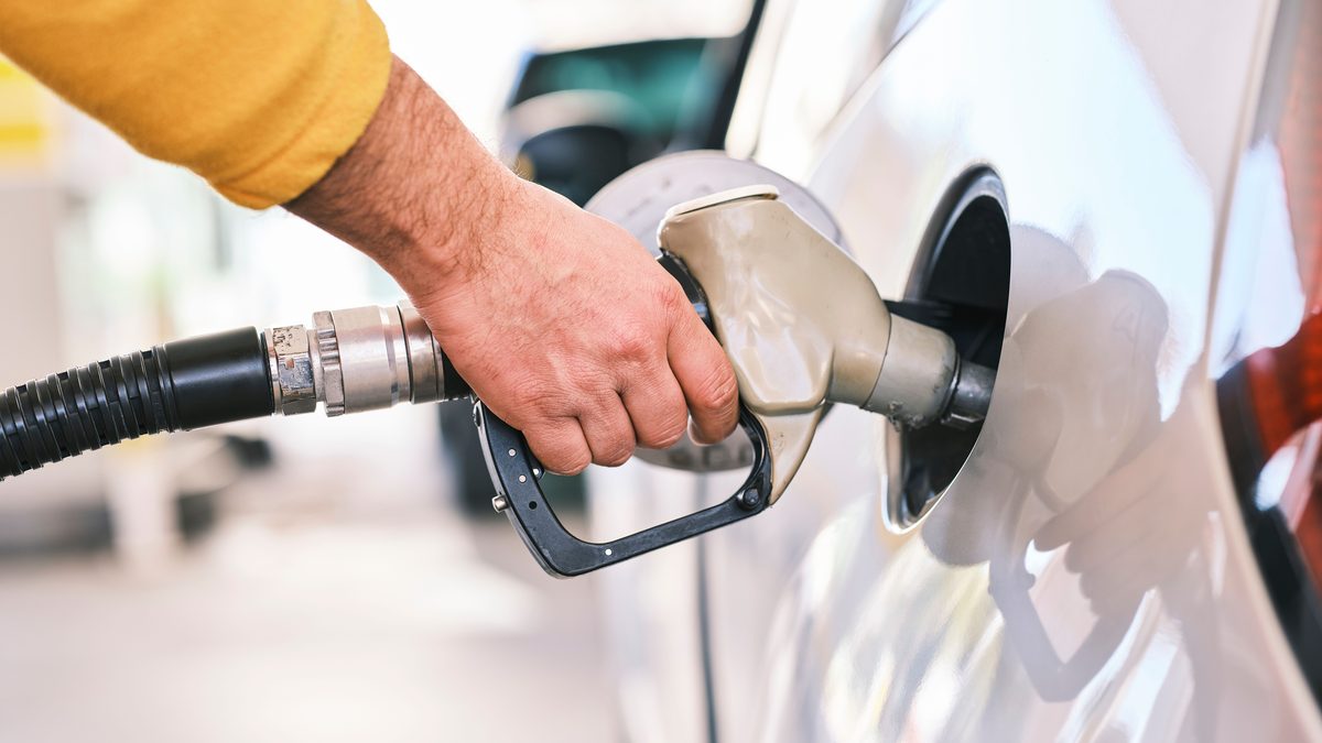 Close-up of a person refueling a car with a gas nozzle at a station.