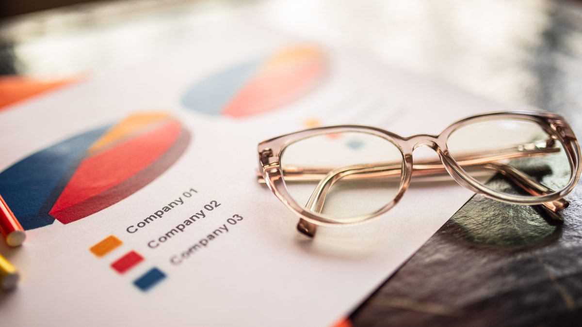 Close-up of eyeglasses on a table with colorful business charts.