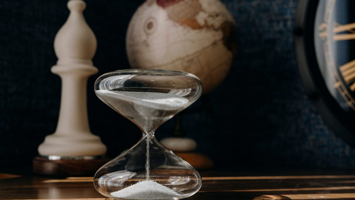A vintage hourglass with a globe and clock, symbolizing time and travel.