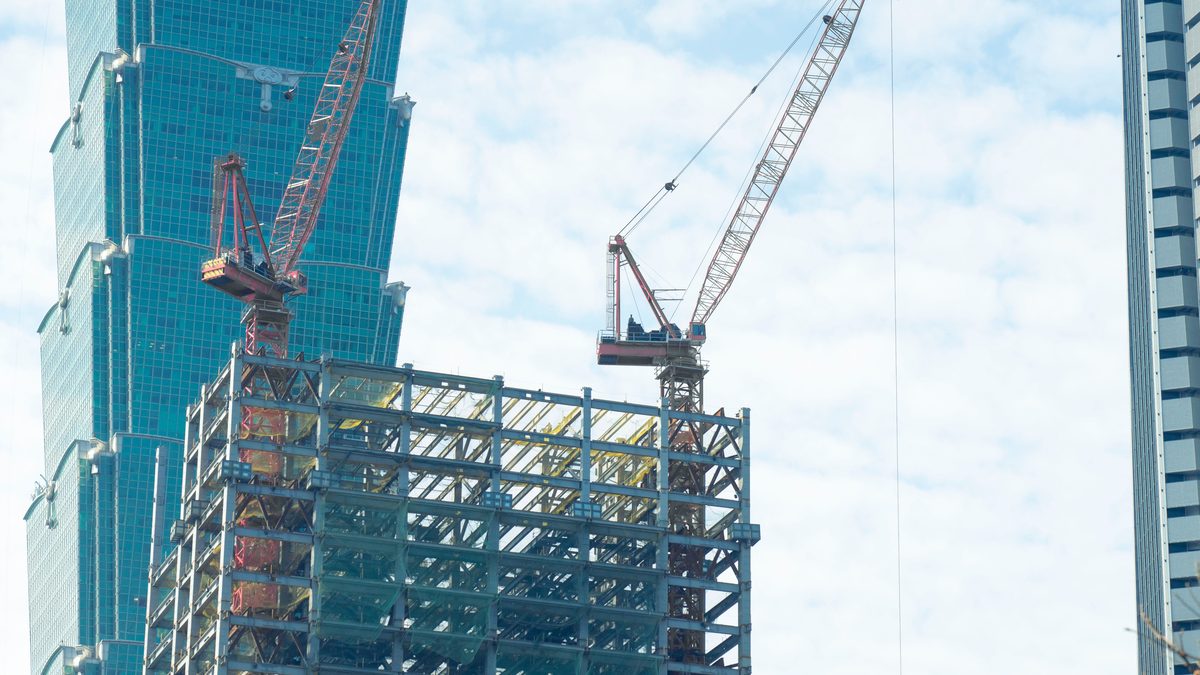 Cranes at construction site in Taipei with Taipei 101 in the background.