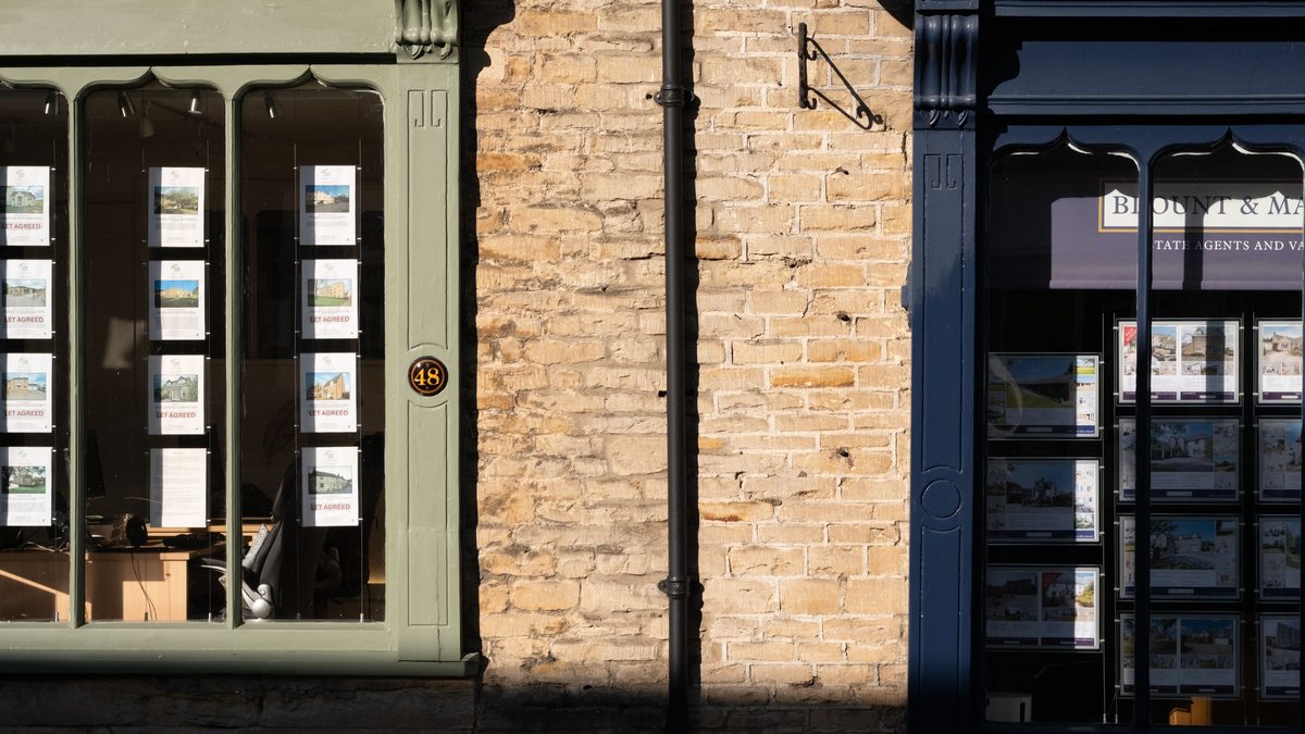 Sunlit display windows of an estate agency in Malmesbury, England.
