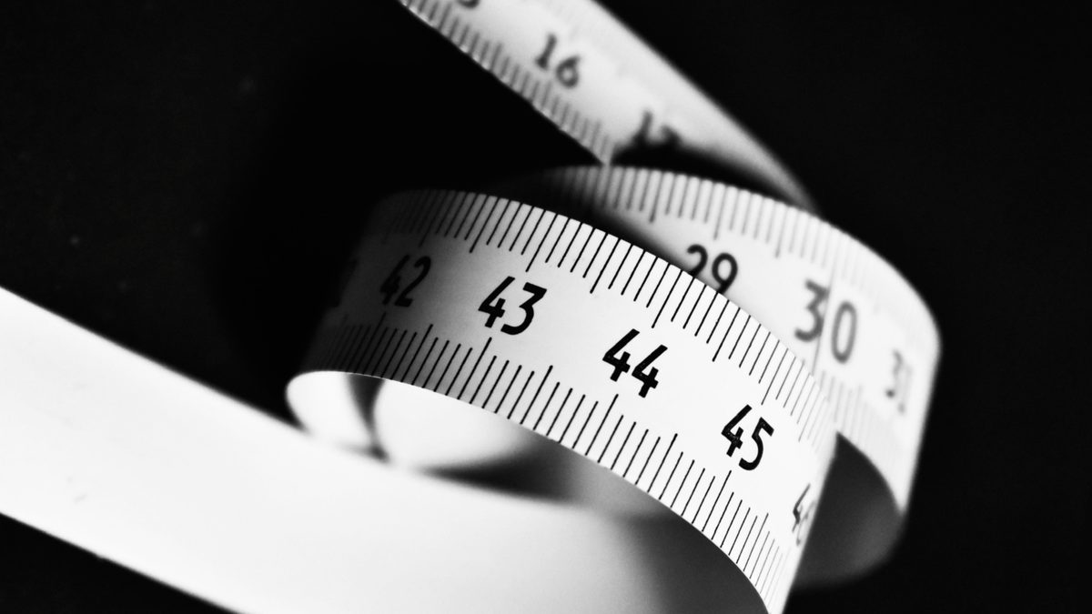 Curved white measuring tape with numbers 15 to 45 on a dark background.