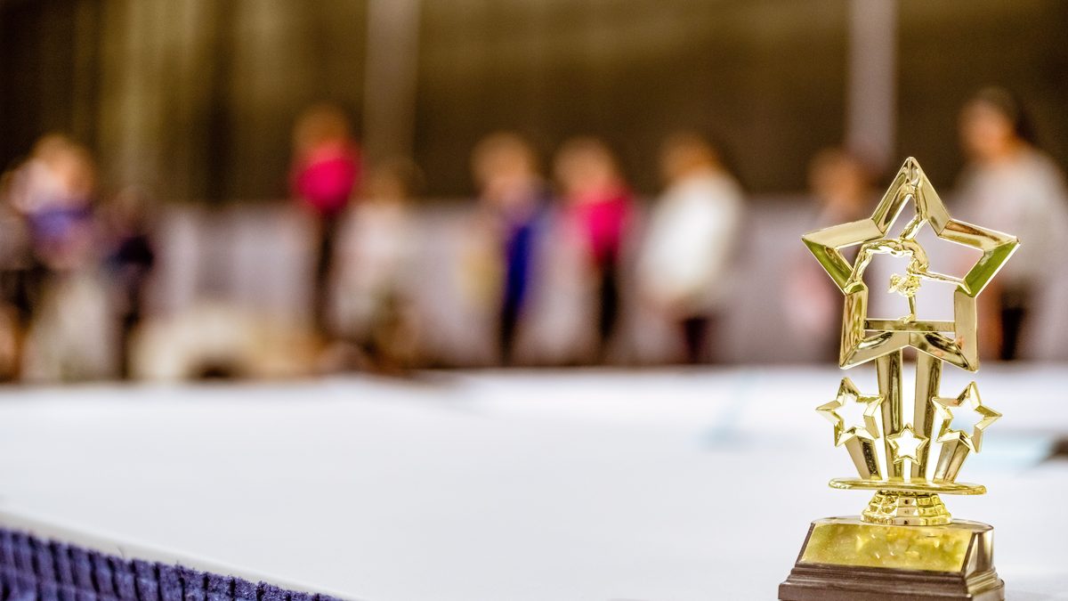 Star-shaped trophy on a table with blurred people in the background at an indoor event.