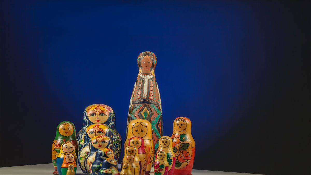 Colorful Russian nesting dolls creatively arranged on a reflective surface with a deep blue background.