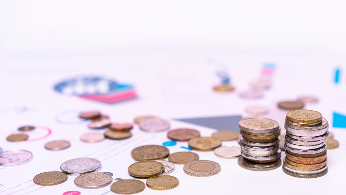 Stack of assorted coins with financial documents on a white background, highlighting the concept of savings.