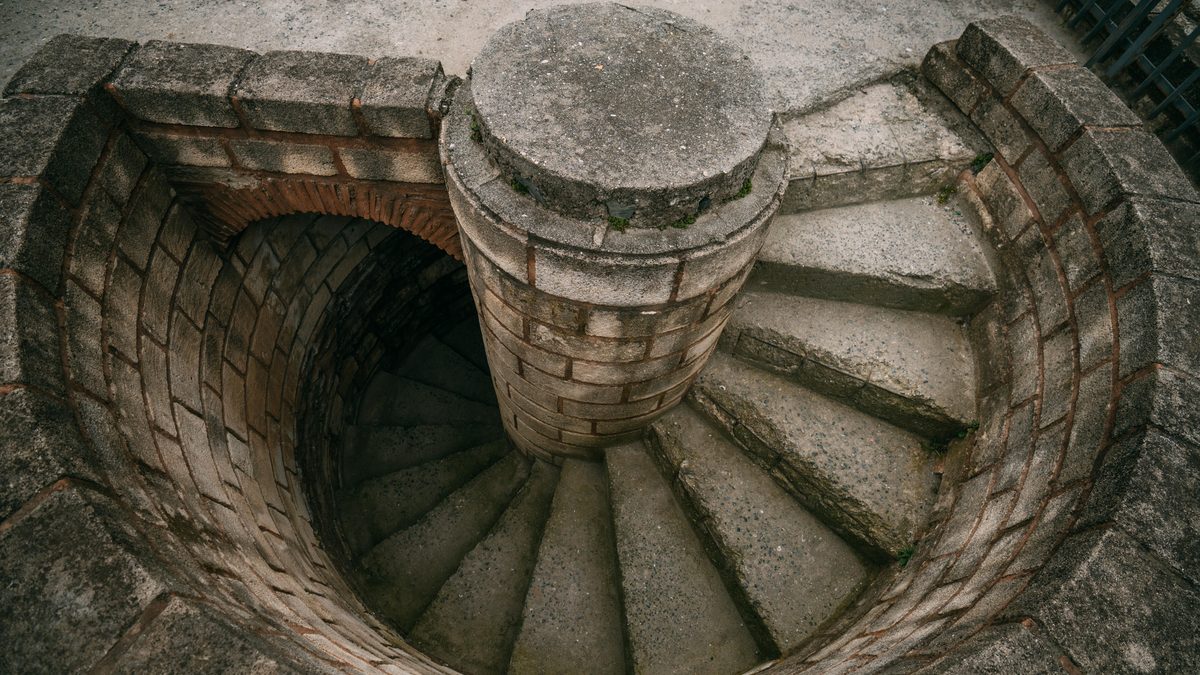 Top view of a spiraling stone staircase outdoors, showcasing architectural beauty.