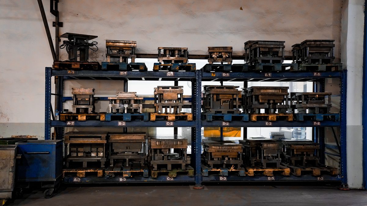 Metal molds neatly arranged on industrial shelving in a warehouse setting, showcasing order and efficiency.