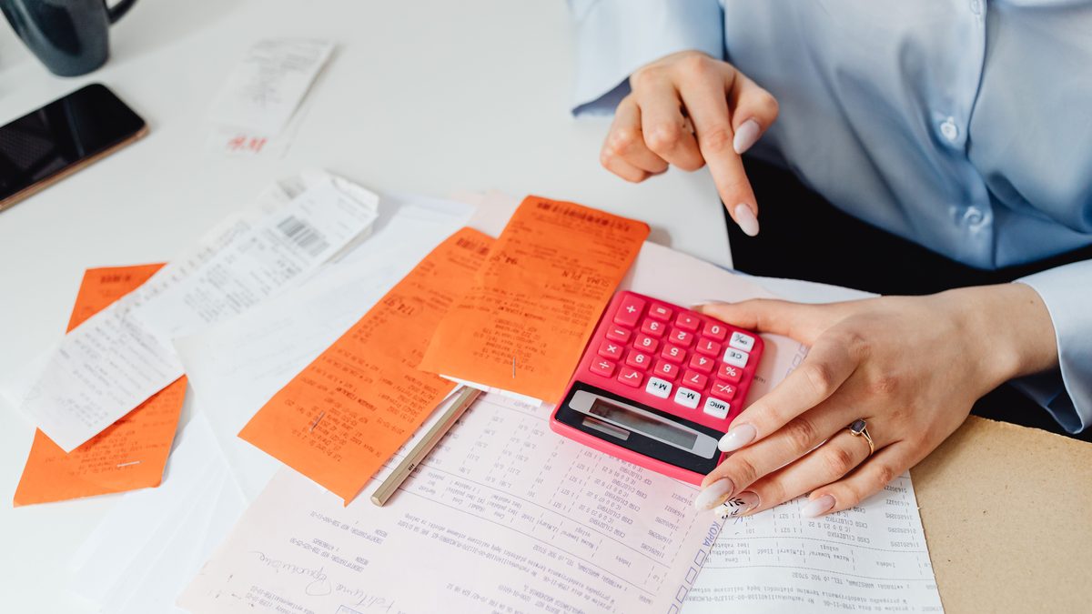 Businesswoman calculates expenses using receipts and calculator at desk. Ideal for finance, accounting themes.