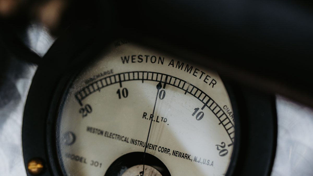 Close-up of a vintage Weston Model 301 ammeter, its needle resting at zero between the discharge and charge halves of the dial.