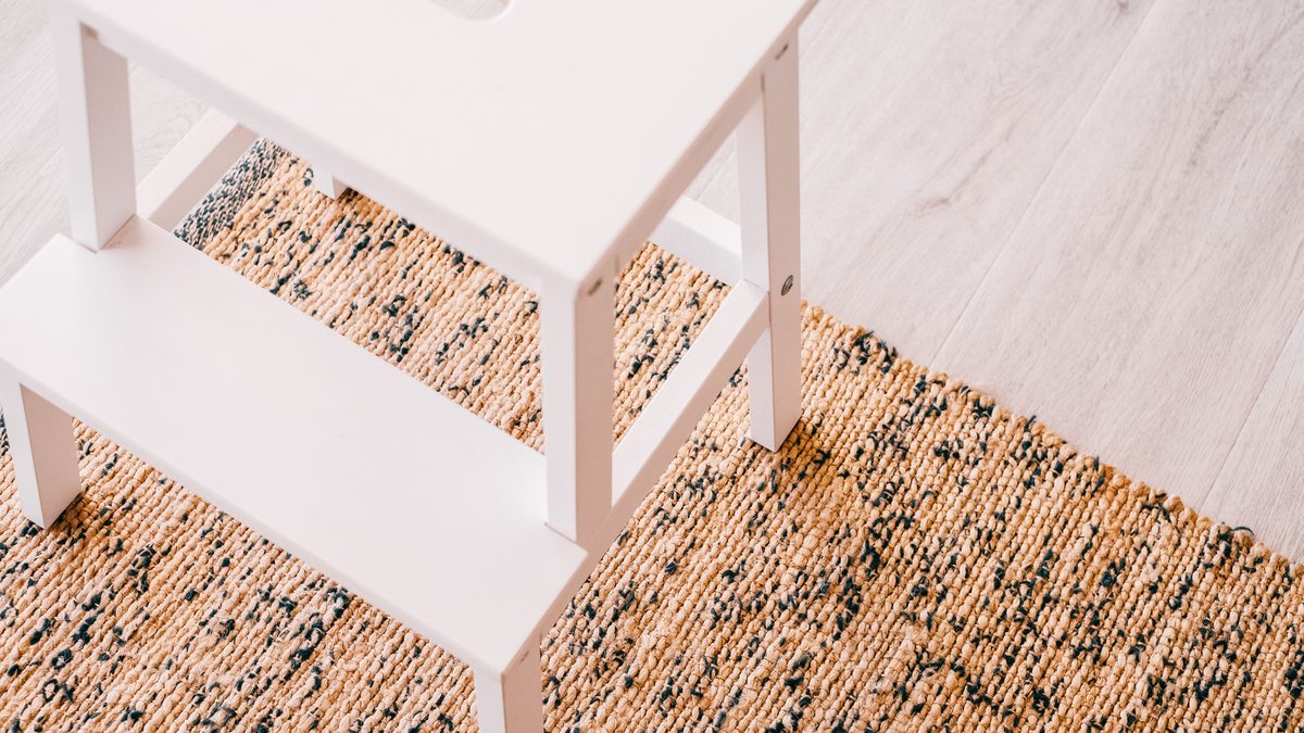 A clean, minimalist stepladder on a natural woven rug in a stylish interior.