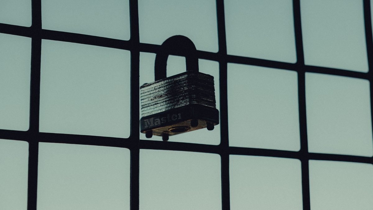Close-up of a steel padlock on a mesh fence, symbolizing protection and security.