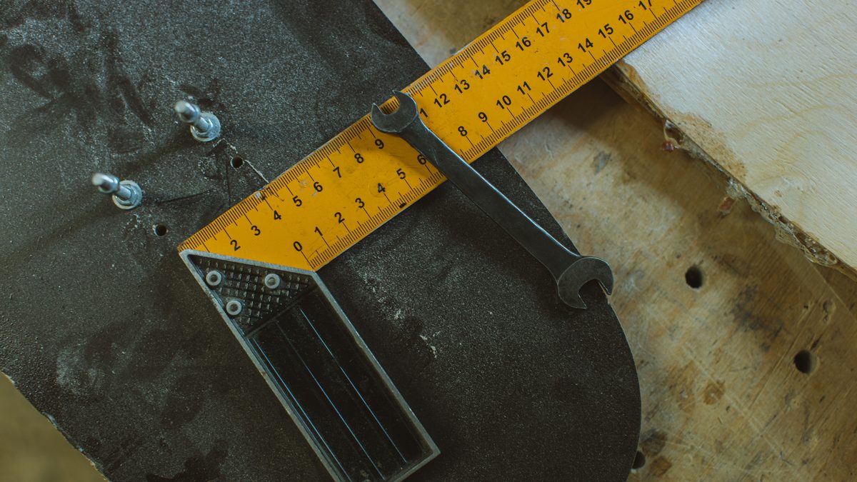 Detailed view of skateboard assembly tools including ruler and wrench on a wooden workbench.