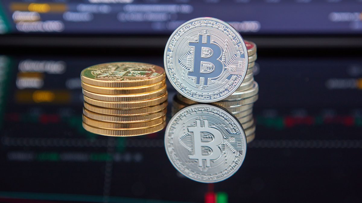 Bitcoin coins stacked in front of cryptocurrency trading chart reflecting market trends.