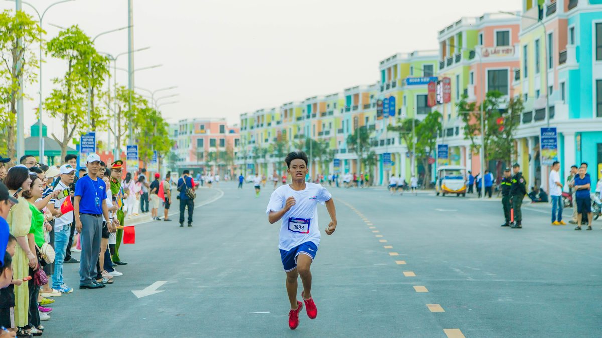Runner reaching the finish line in a vibrant marathon in Hải Phòng's colorful streets.
