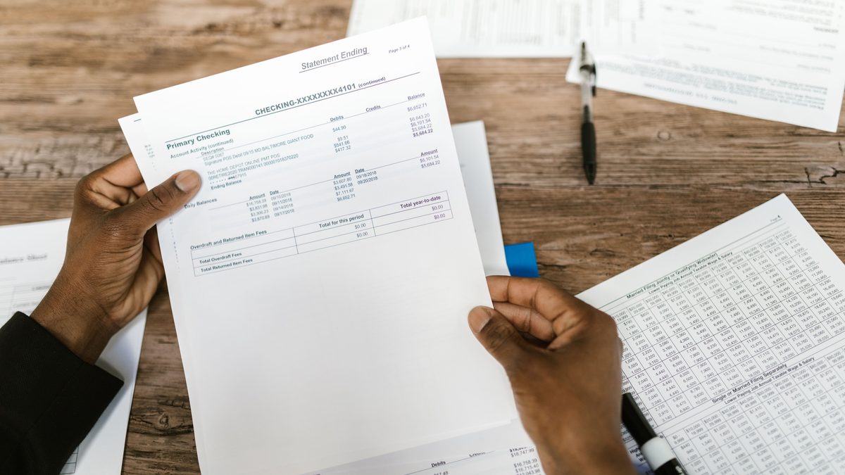 Hands holding financial papers for tax preparation and analysis.