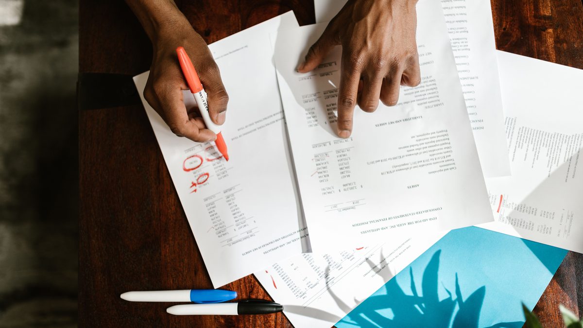 Overhead view of hands highlighting financial documents on a desk.