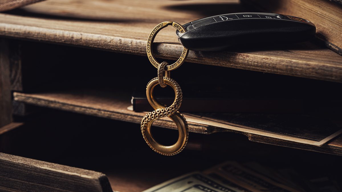 A car key and an infinity-symbol keychain resting on a rustic wooden desk.