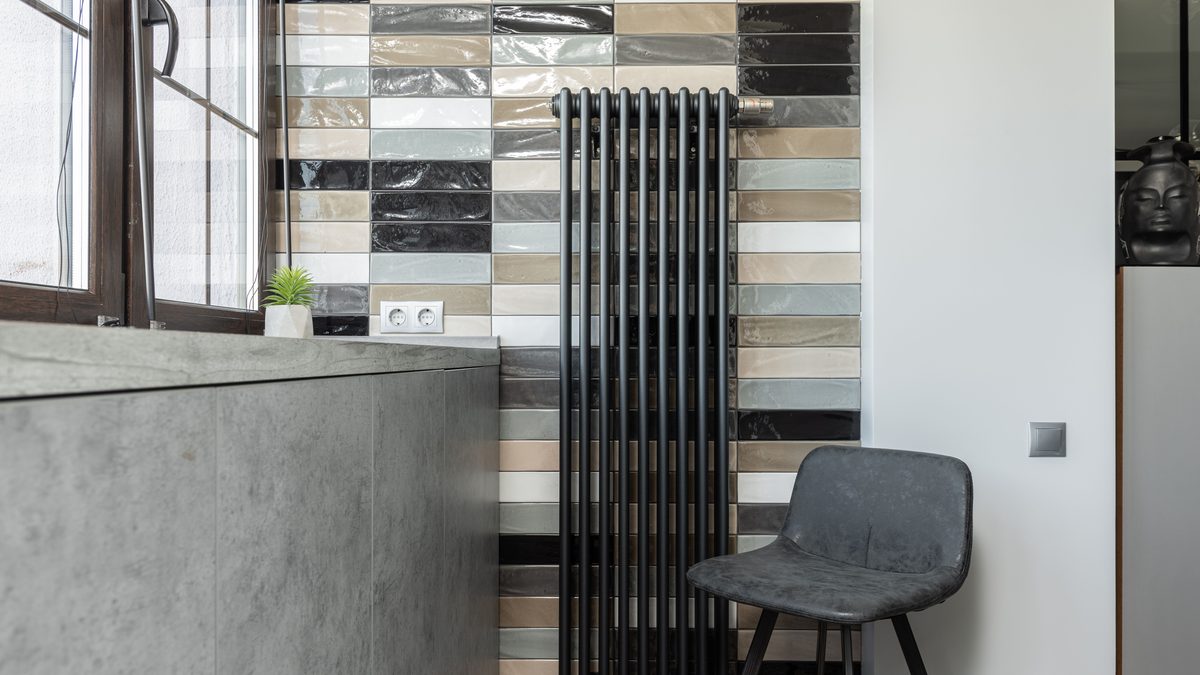 Stylish home interior featuring a tiled wall, radiator, and designer chair.