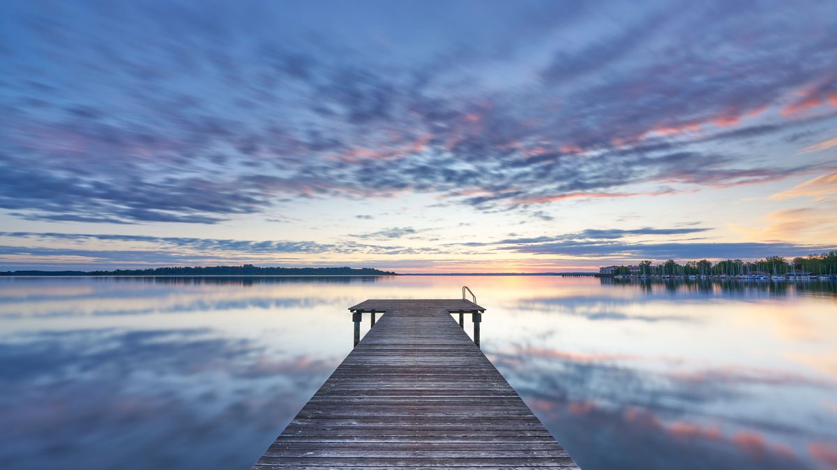 Peaceful sunrise view from a wooden pier over Chiemsee lake in Bavaria, Germany.